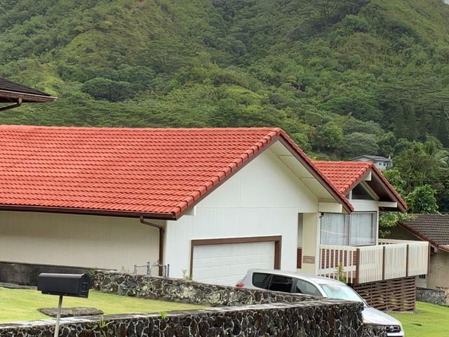 A white house with a red tile roof and mountains in the background