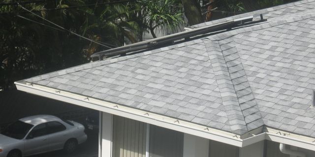 A white car is parked under the roof of a house.