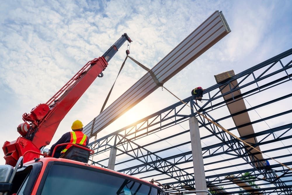 Crane lifting a long, rectangular beam at a construction site.