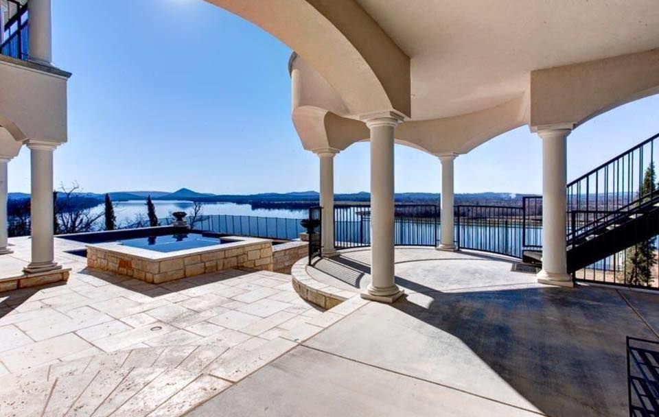 Covered patio with columns overlooking a pool and distant water view