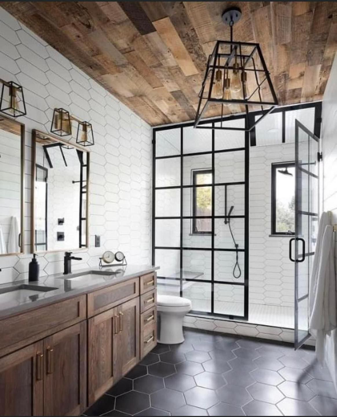 Modern bathroom with wood vanity, black-framed glass shower, and hexagonal tile floor