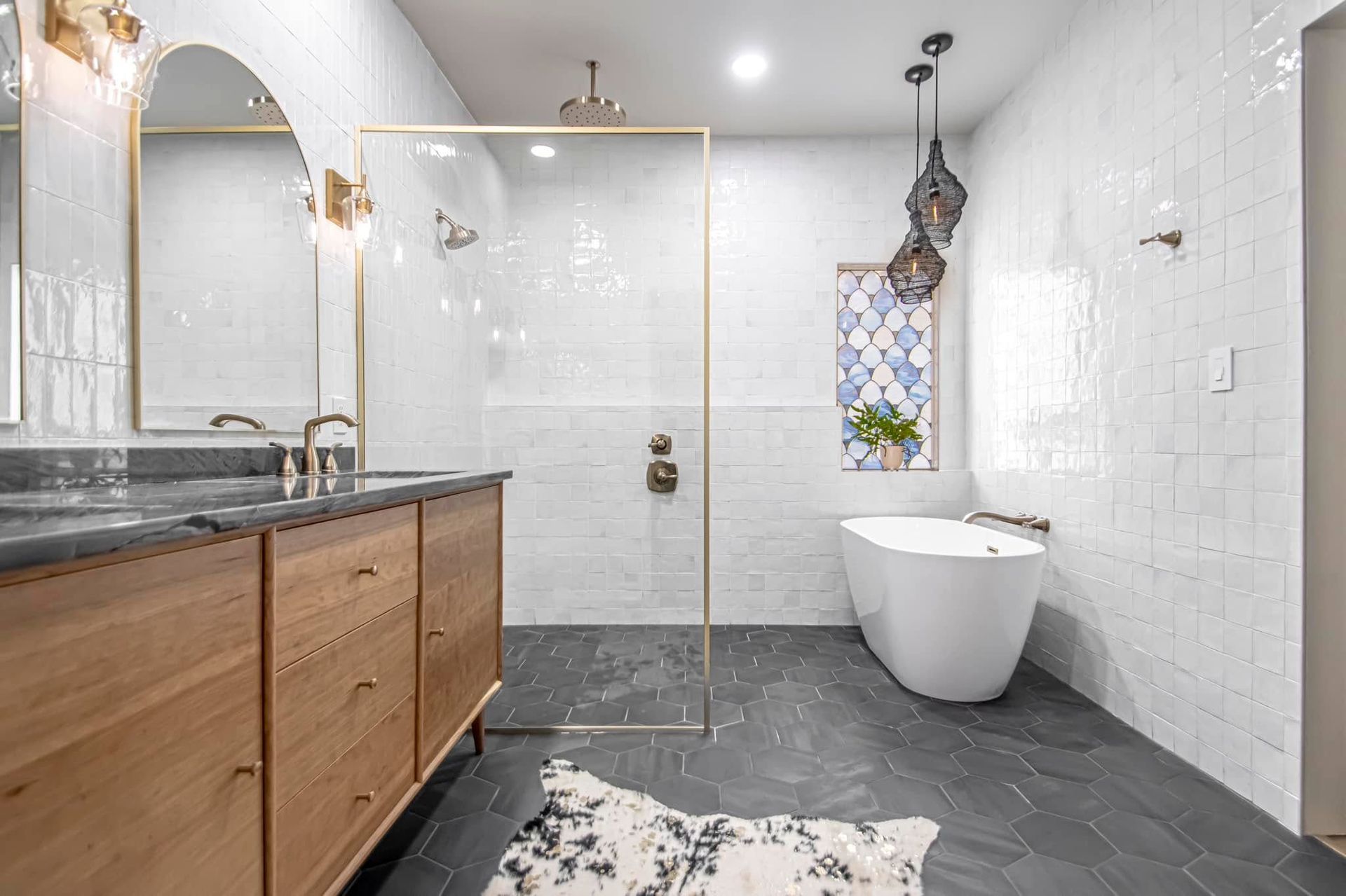 Modern bathroom with walk-in shower, freestanding tub, wood vanity, and dark slate floor