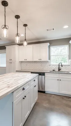 Bright white kitchen with marble island, pendant lights, and stainless appliances
