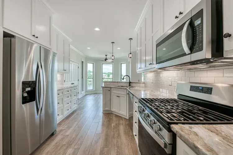 Bright modern kitchen with stainless steel appliances, white cabinets, and a central island.