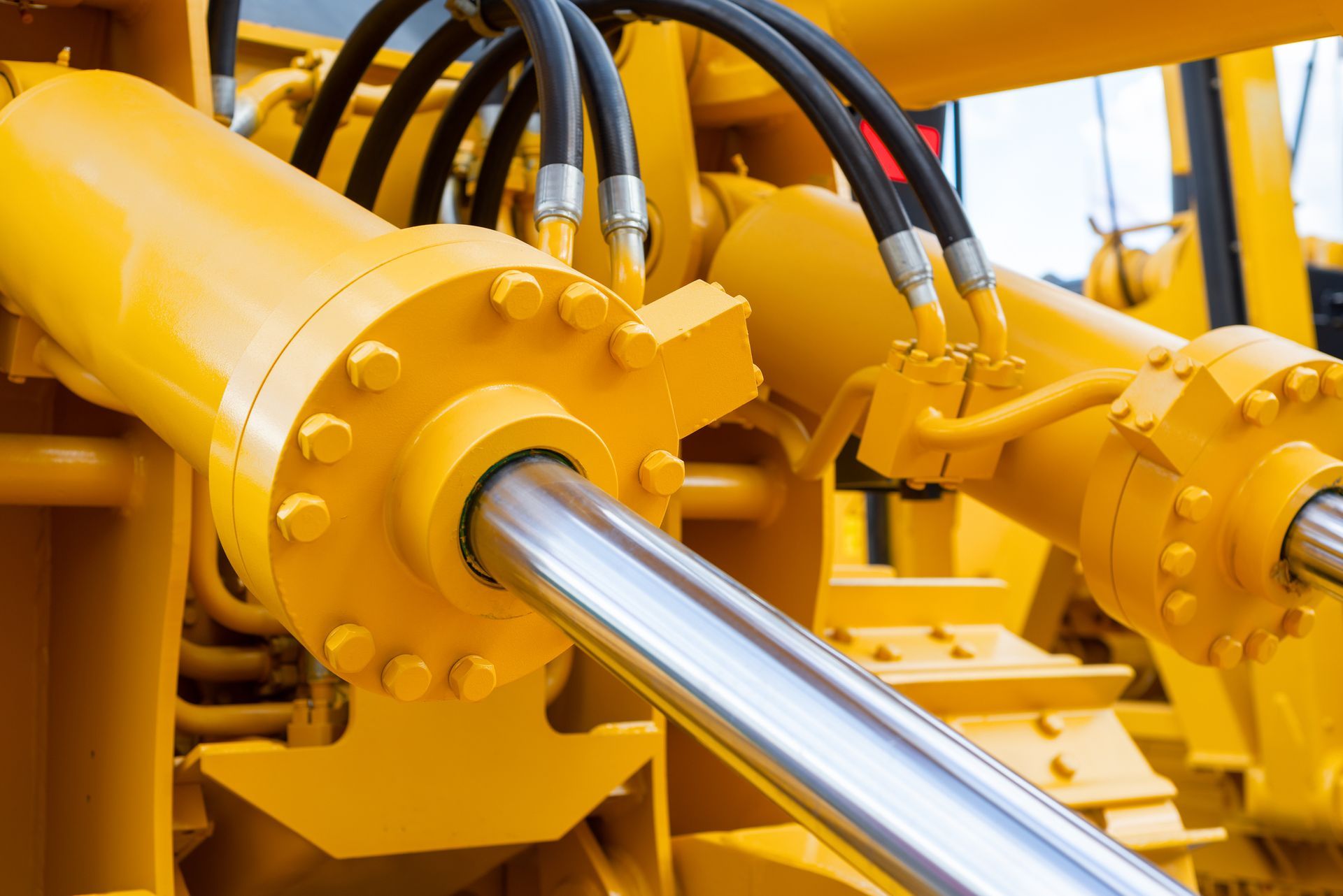 Close-up image of yellow hydraulic equipment with pipes.