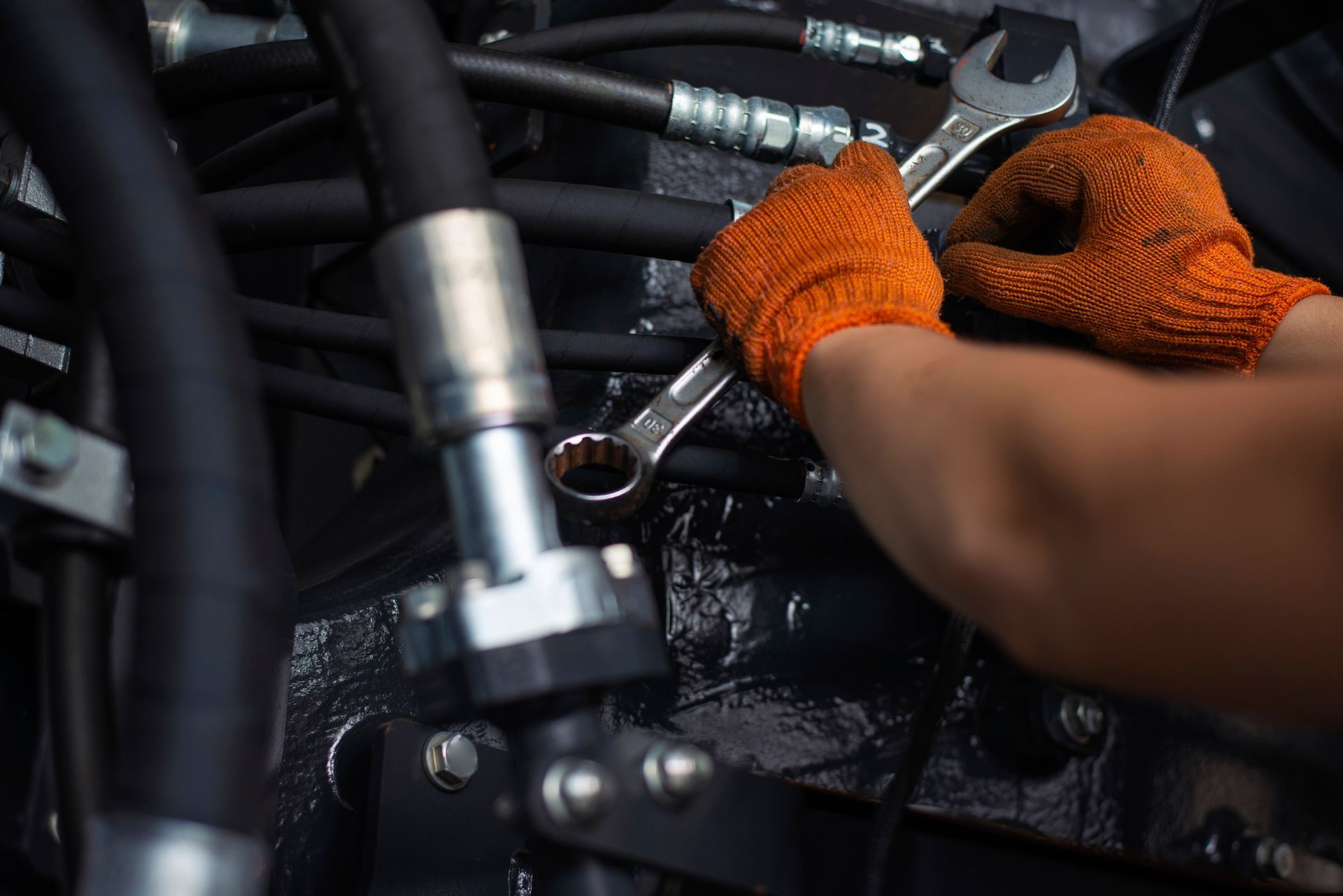 A person is working on a car engine with a wrench.