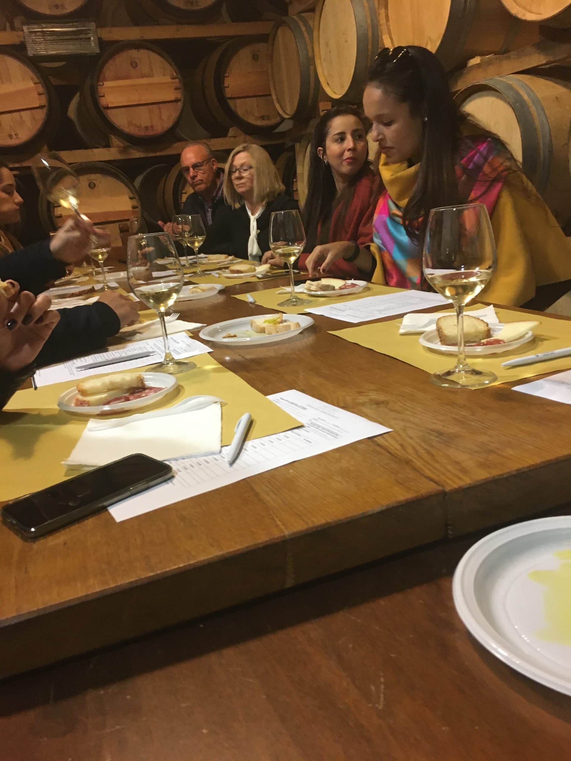 Group seated around a wooden table in a restaurant, sharing a meal with plates and drinks.