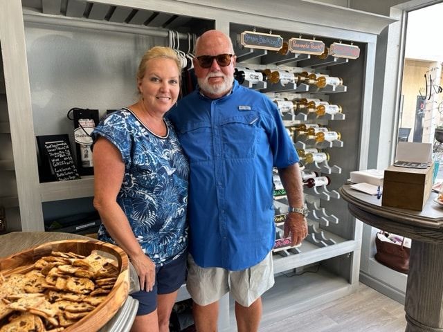 Two people standing inside a shop beside a display of packaged items and a basket of bread.