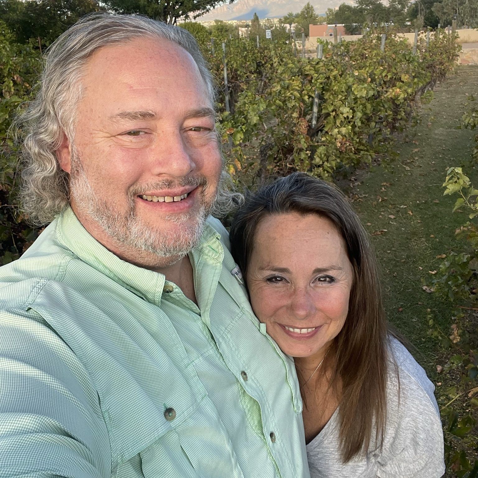 Smiling couple taking a selfie in a green orchard at sunset