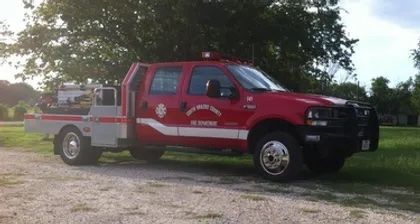 A red fire truck is parked in a gravel lot