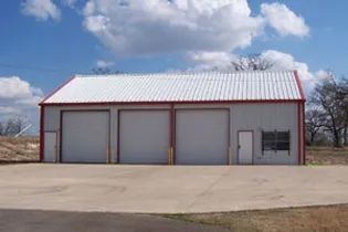 A fire station building with a red trim has a lot of garage doors