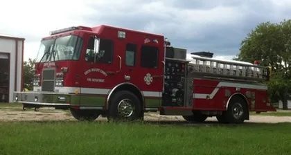 A red fire truck is parked in a grassy field