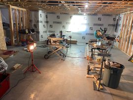 Bright unfinished modern room with large windows, high ceilings, and exposed construction materials inside a home