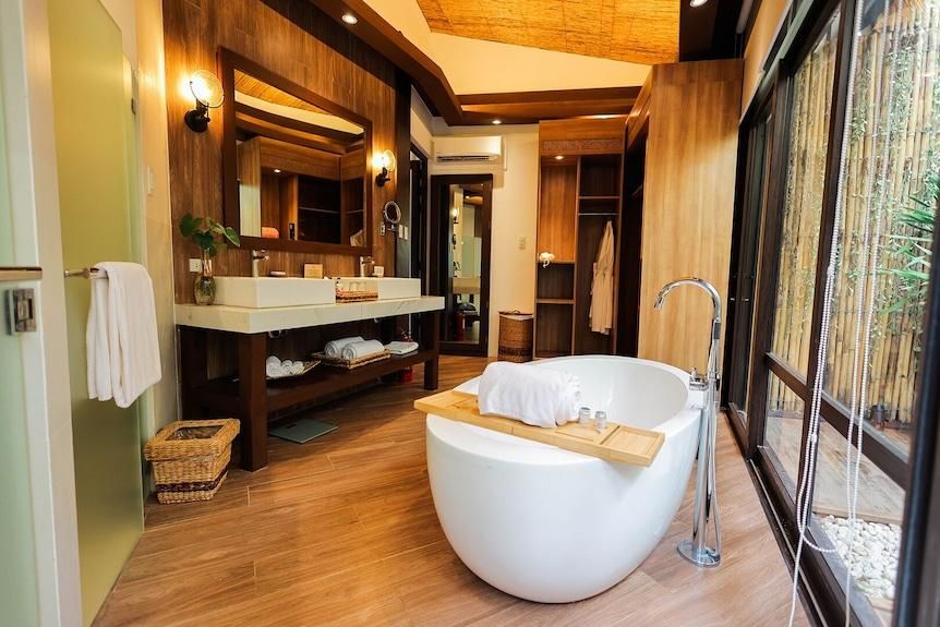 Modern bathroom with a freestanding tub, double sink vanity, and wood-paneled walls