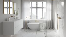 Bright minimalist bathroom with white tub, double vanity, large windows, and gold accents