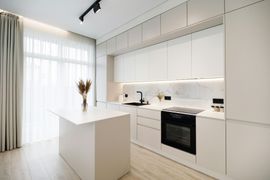 Minimal white modern kitchen with island, built-in appliances, and large window curtains
