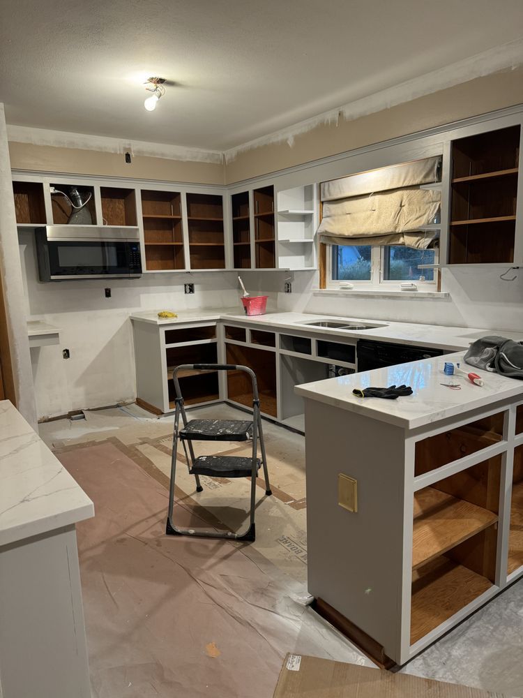 Partially remodeled kitchen with white cabinets, dark countertops, and tools on the floor