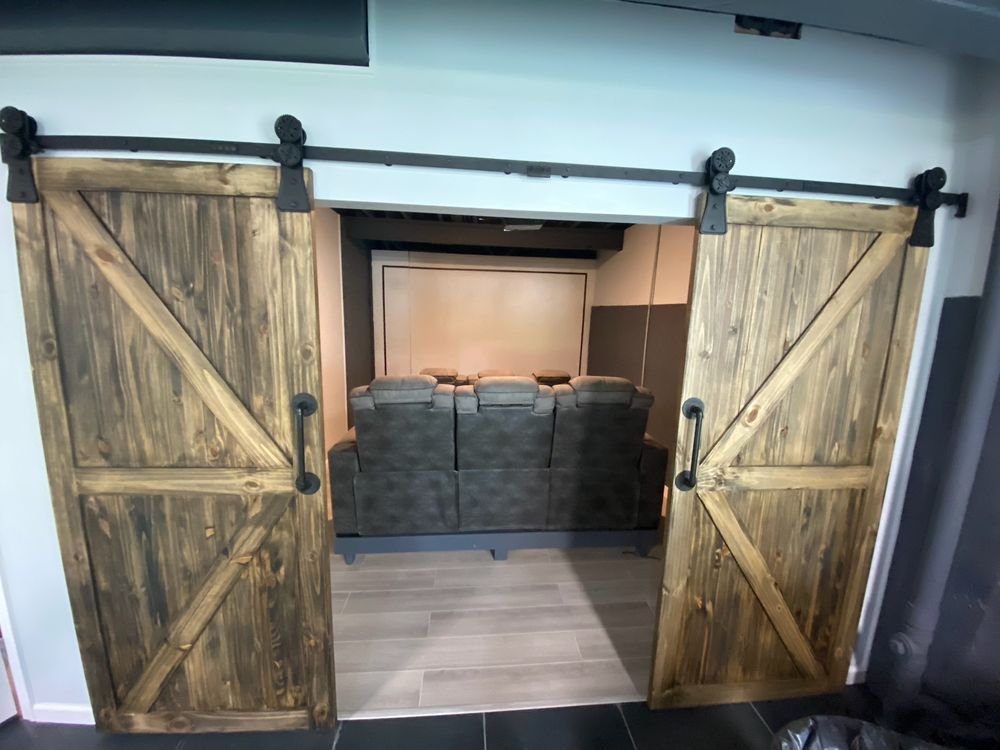 Rustic sliding barn doors open to a living room with a gray sectional sofa.