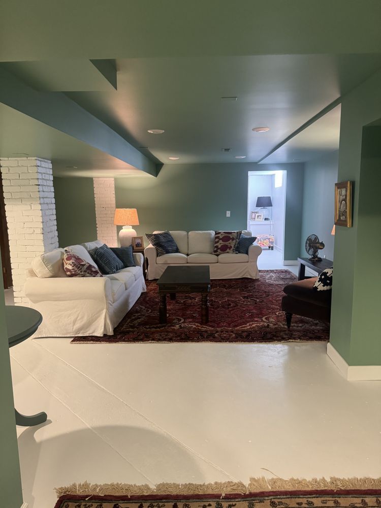 Cozy living room with white sofa, patterned rug, lamps, and a bright doorway in the back