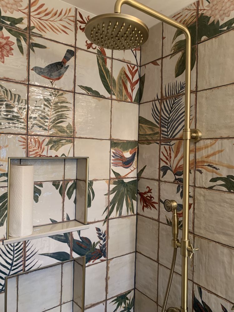 Tropical bird-pattern shower with brass rainfall head and tiled walls