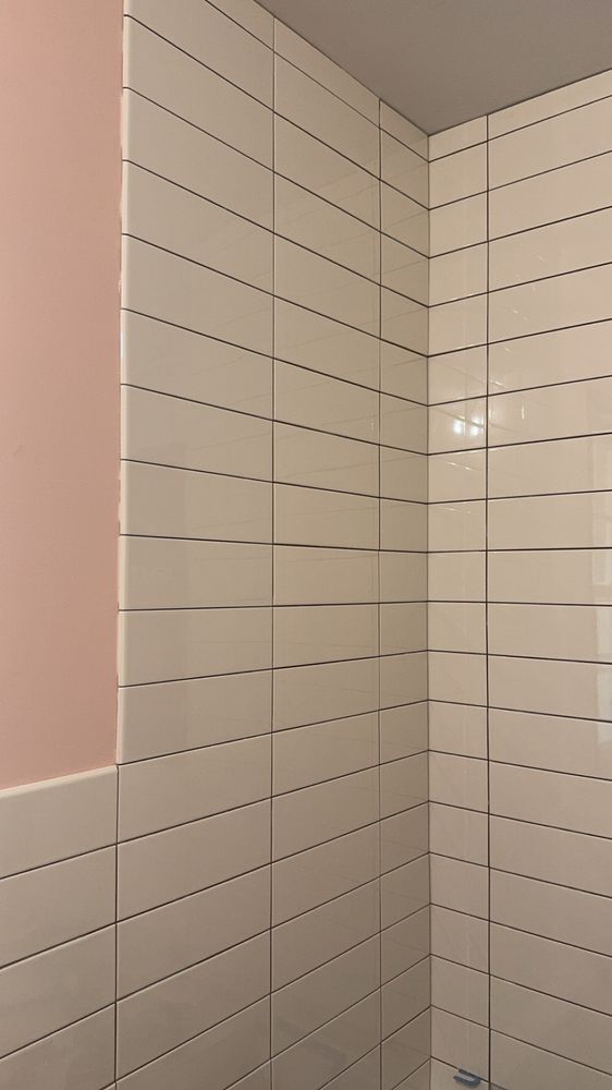 Corner of a bathroom with white subway-tile walls and a pink painted section on the left.