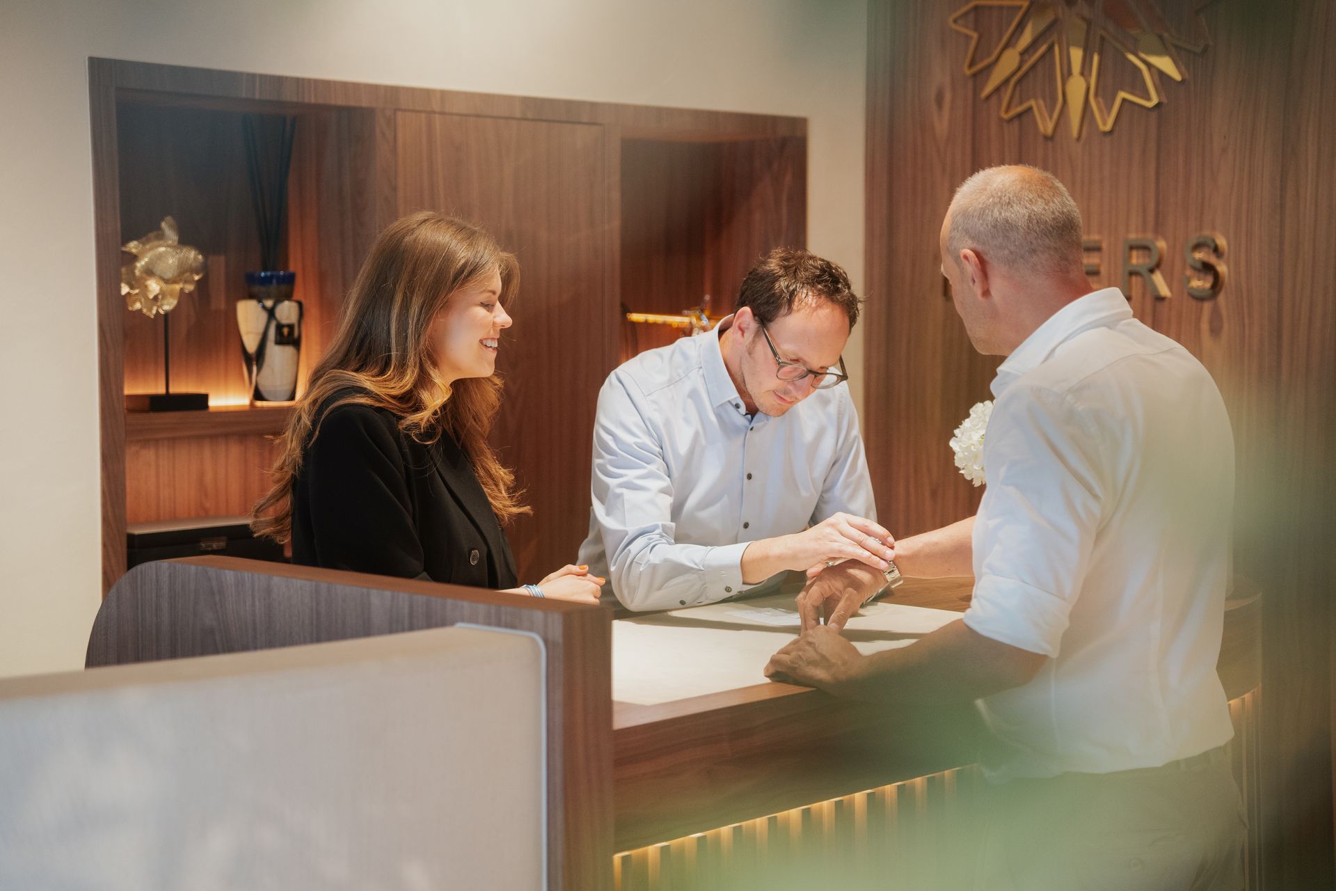 Drie personen bespreken documenten aan de receptie van een hotel.