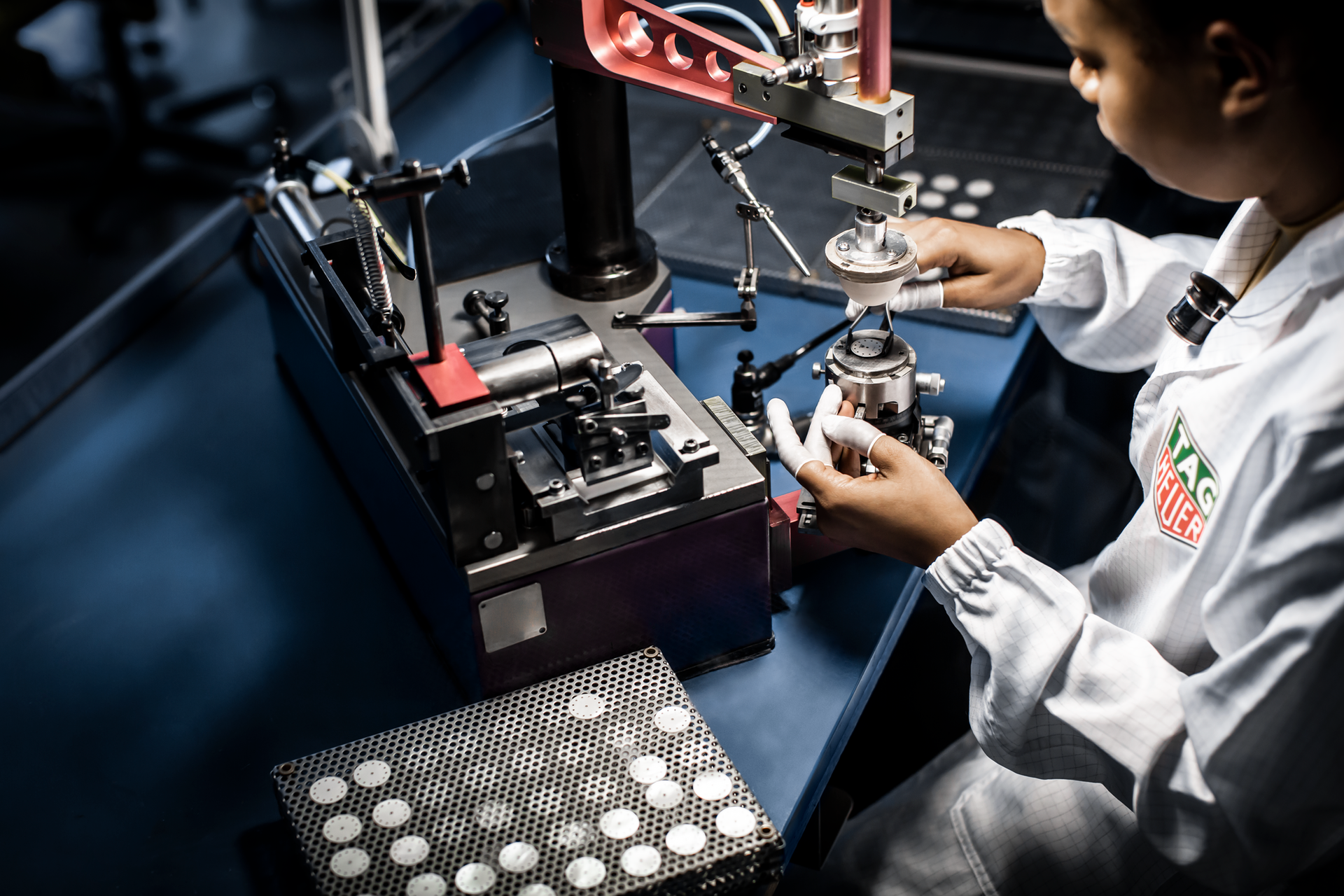 Technicus gebruikt een microscoop om componenten op een laboratoriumwerkbank met elektronische apparatuur te inspecteren.