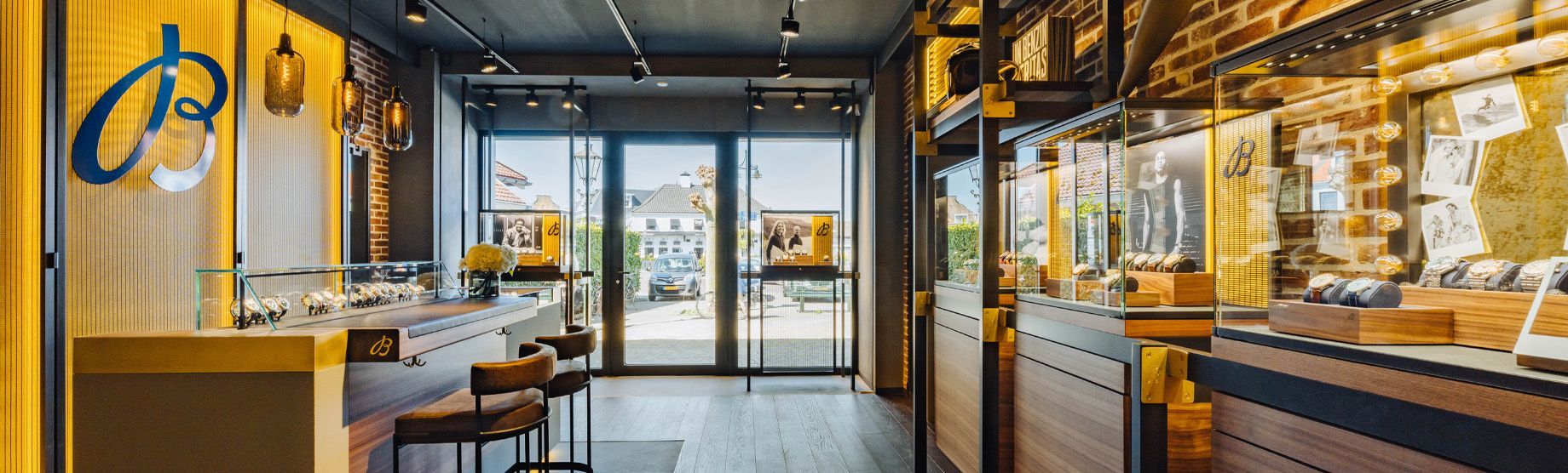 Een sfeervol verlicht café-interieur met houten tafels, een toonbank en glazen deuren bij de ingang.