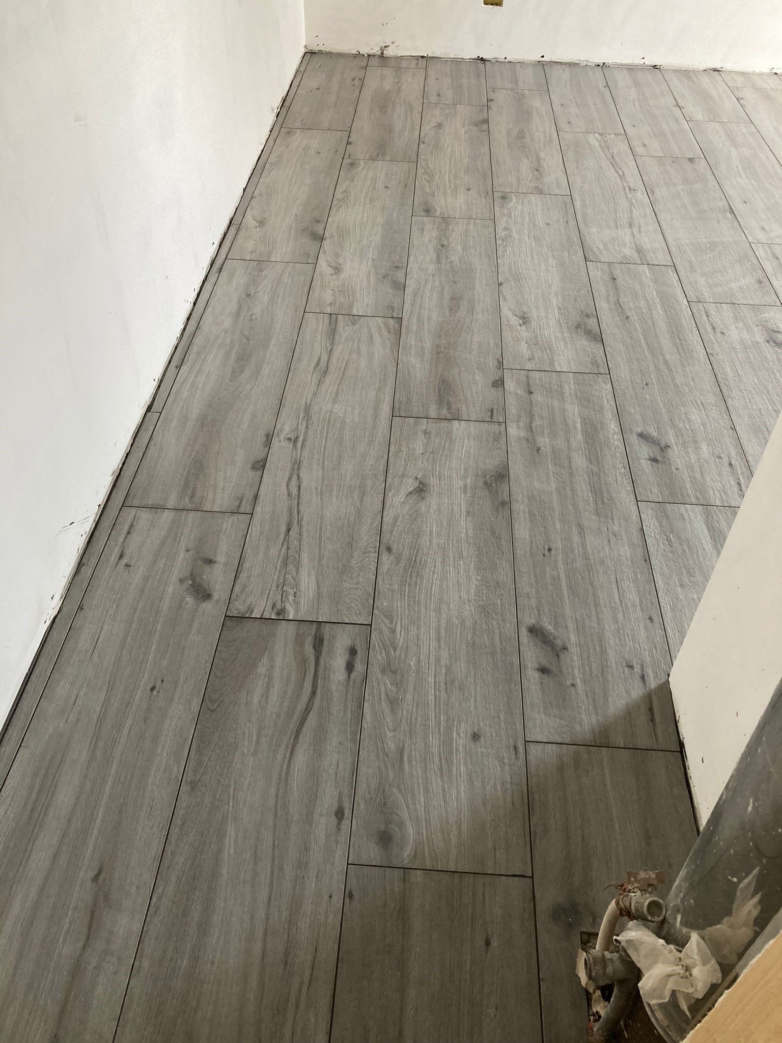 Una stanza con pavimento in legno e parete bianca.