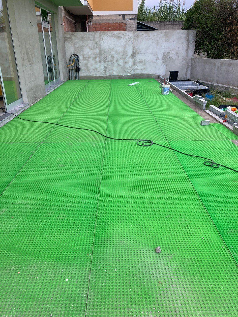 Un tappeto verde ricopre una piscina in un cortile.