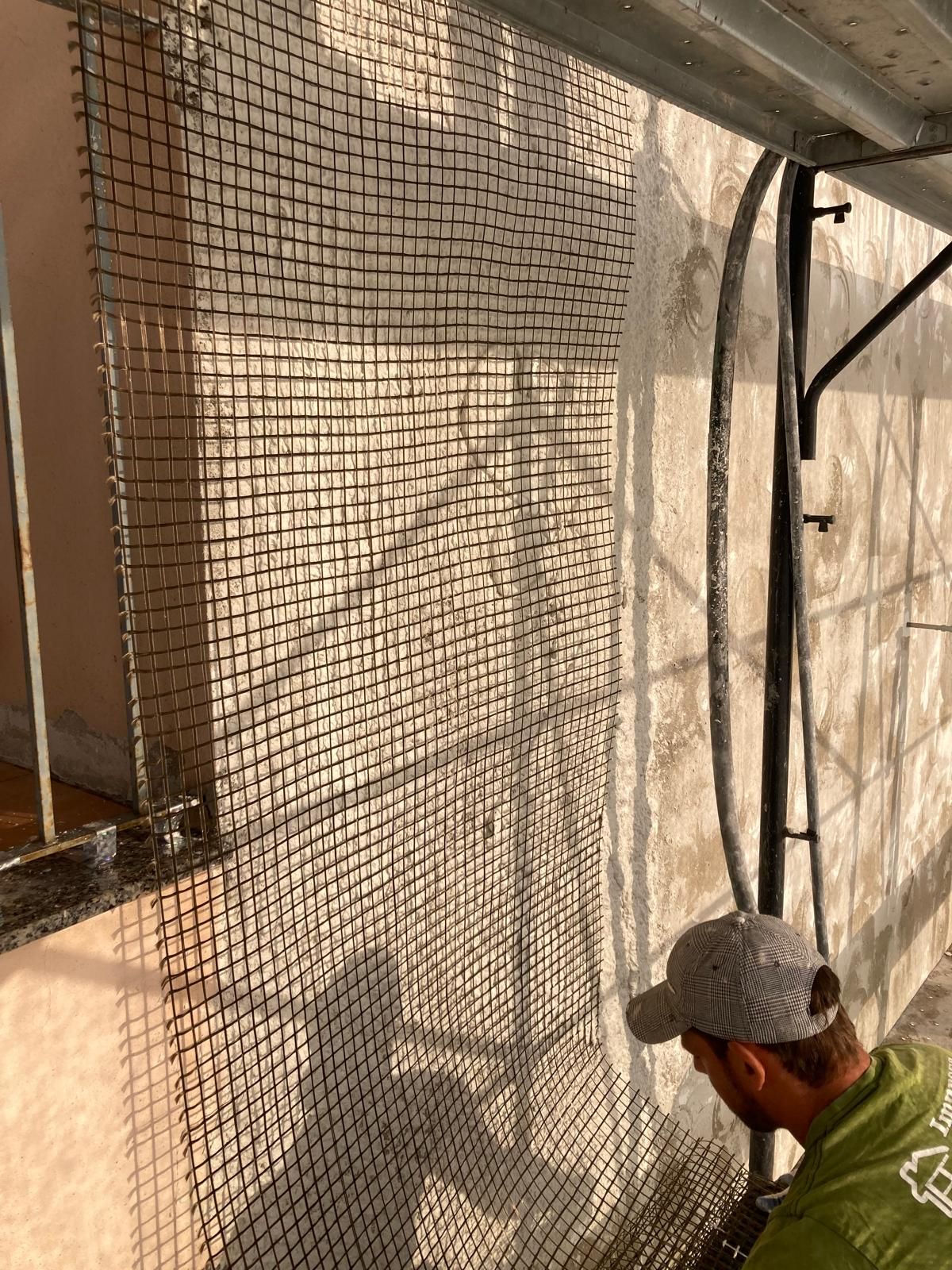 Un uomo è in piedi su un'impalcatura e sta dipingendo un muro.