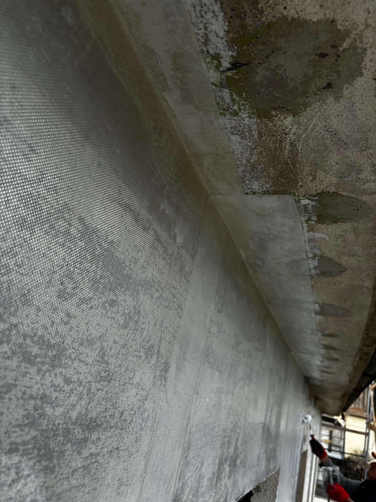 Un primo piano di un muro di cemento con una scala sullo sfondo.