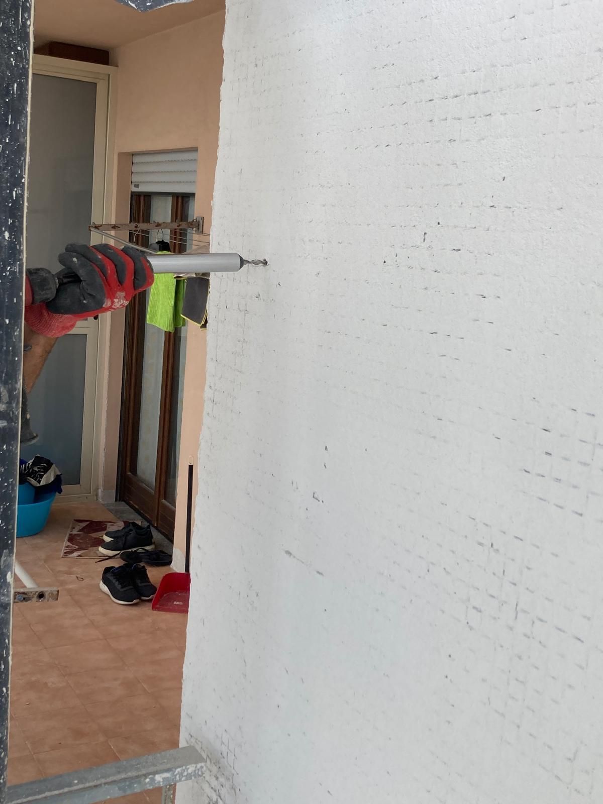 Una persona è in piedi in una stanza con un muro bianco e una finestra.