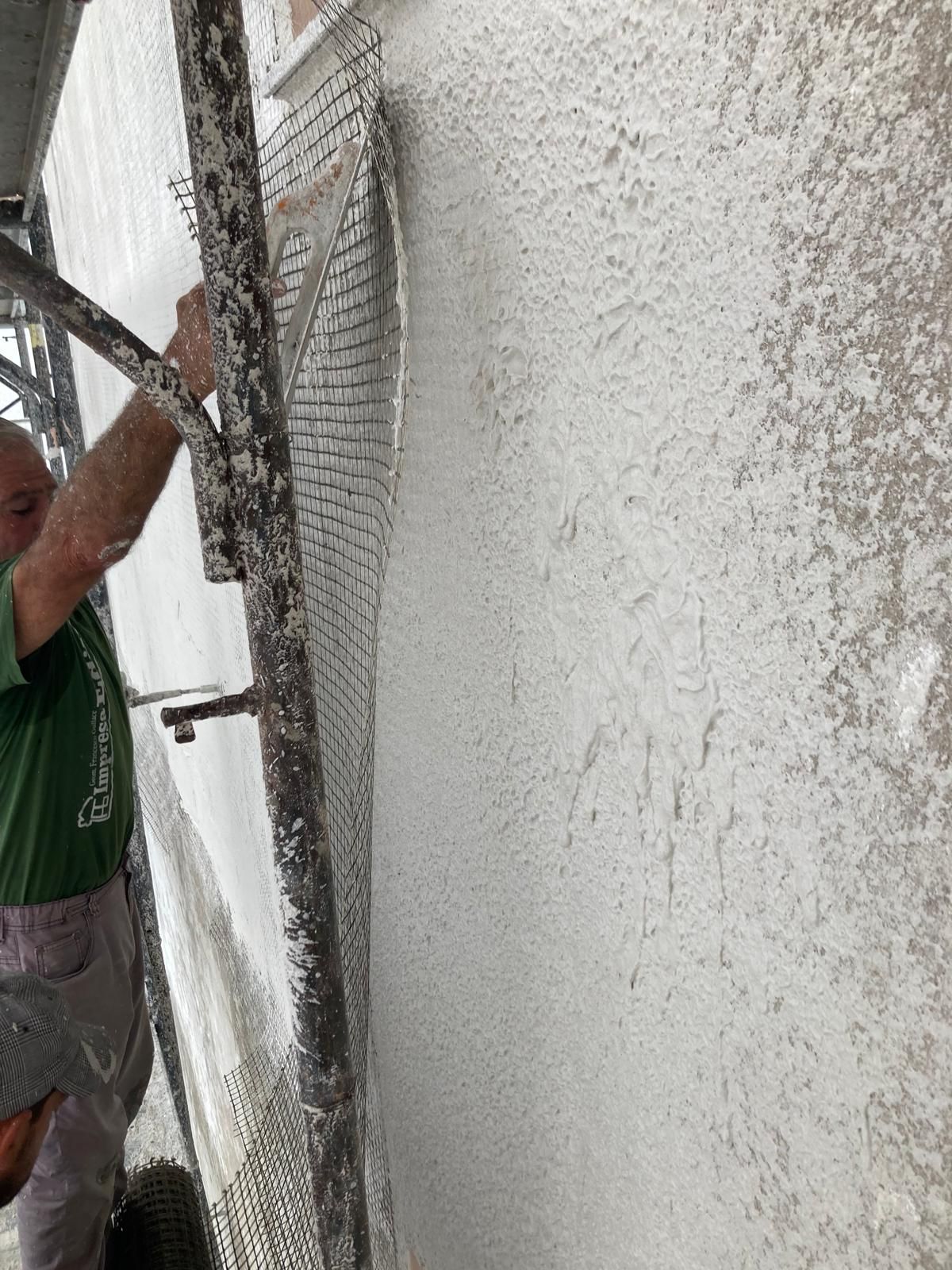 Un uomo è in piedi su un'impalcatura e sta dipingendo un muro.