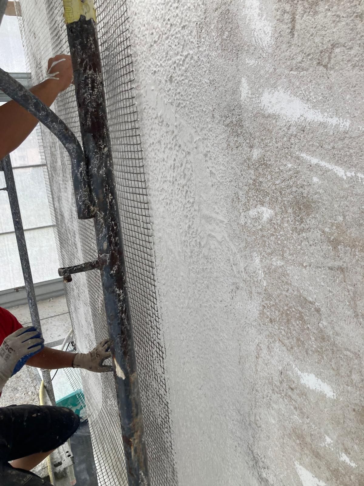 Un uomo è in piedi su un'impalcatura e sta dipingendo un muro.
