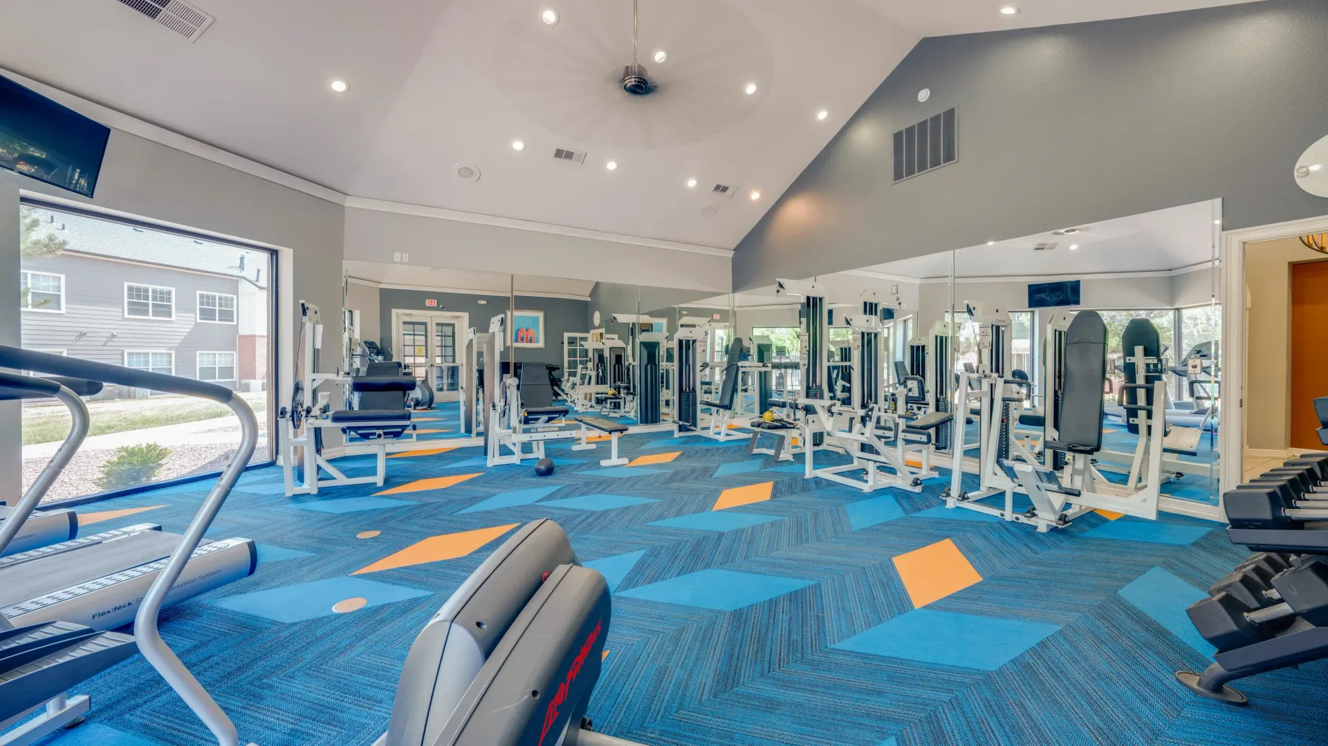 Fitness center with treadmills, weight machines, and dumbbells.