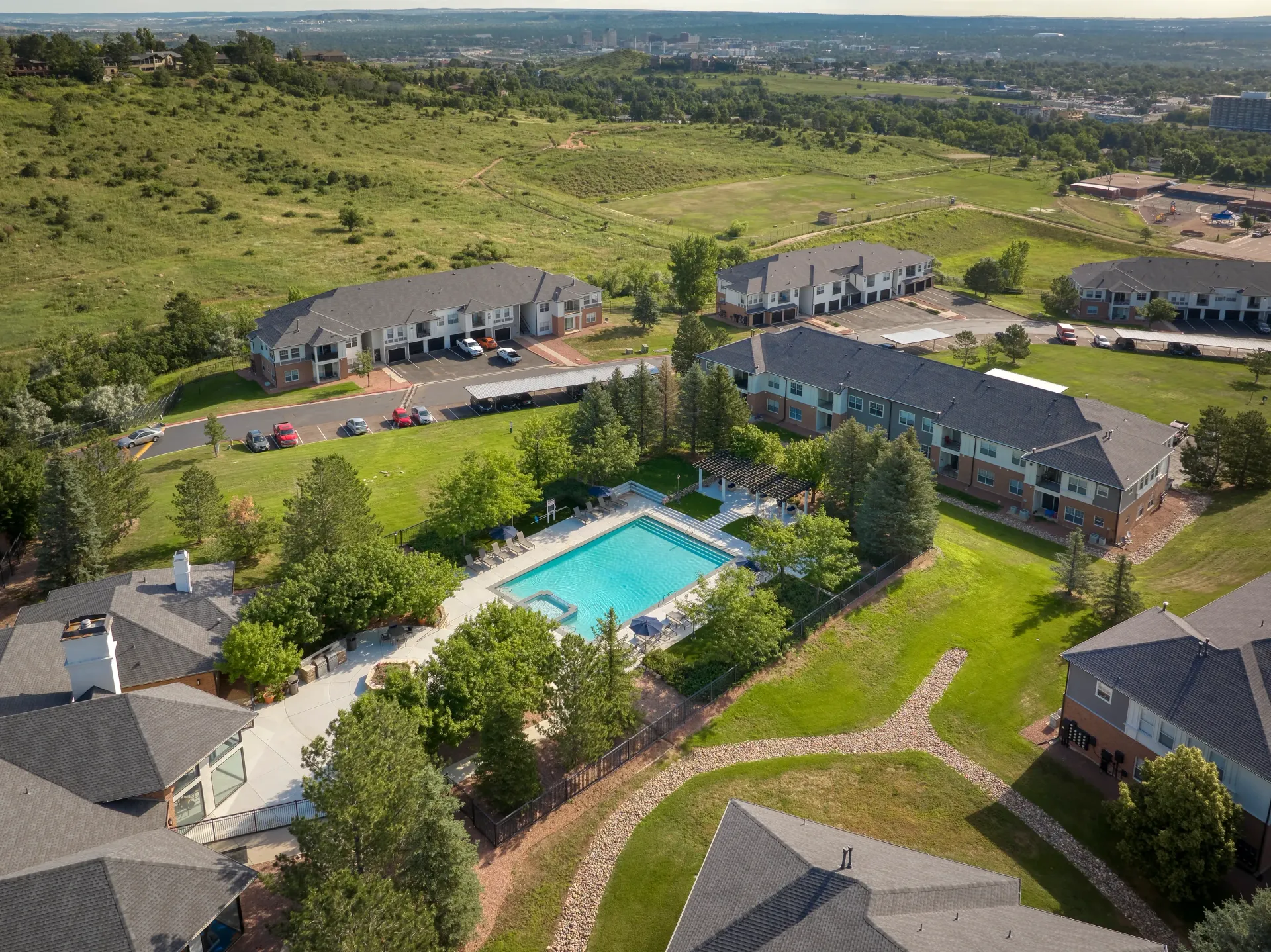 Aerial view of apartment buildings surrounding a large outdoor swimming pool and hot tub area.