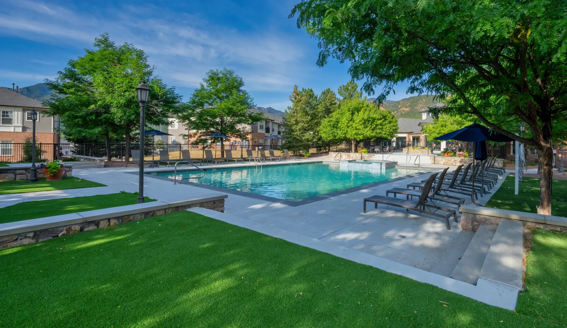 Outdoor swimming pool area with lounge chairs and surrounding buildings.