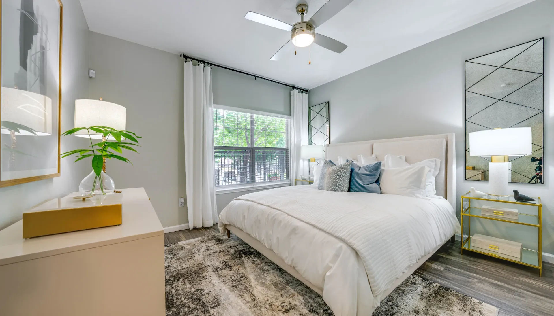 Modern bedroom with a large white bed, ceiling fan, and a dresser.