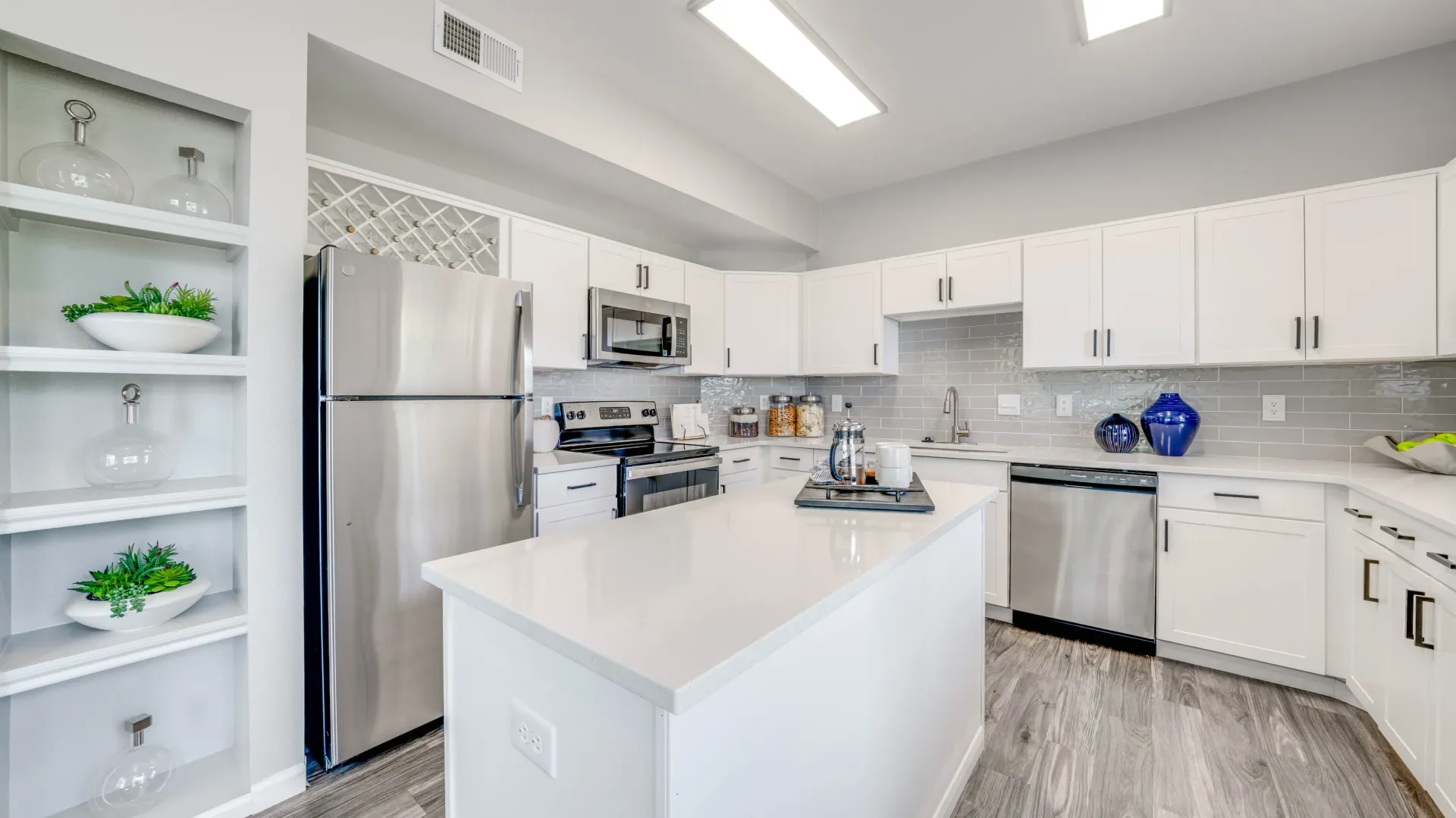 Modern kitchen with stainless steel appliances, white cabinets, quartz countertops, and island.