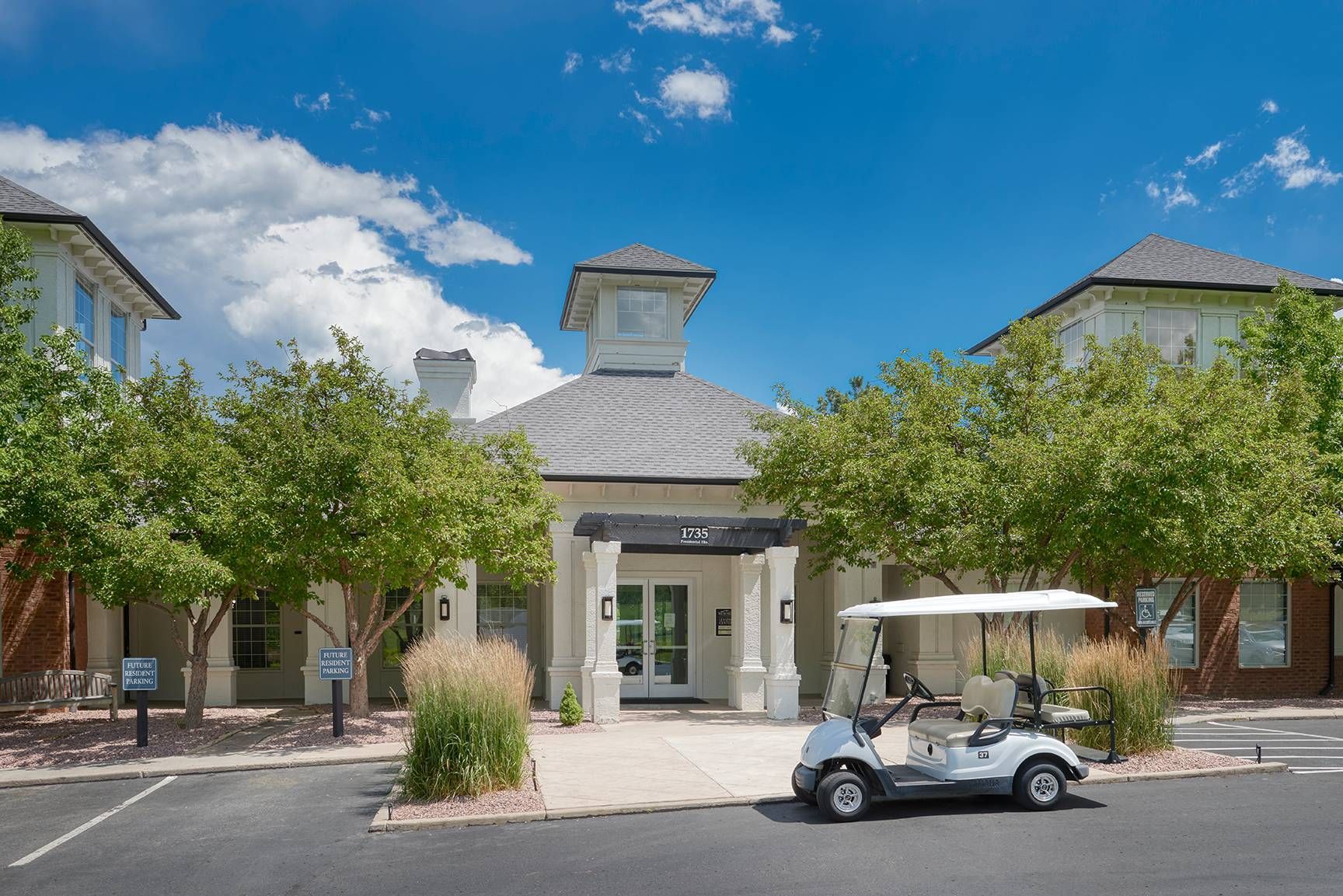 Exterior view of a modern apartment community entrance with a covered entry and landscaping.