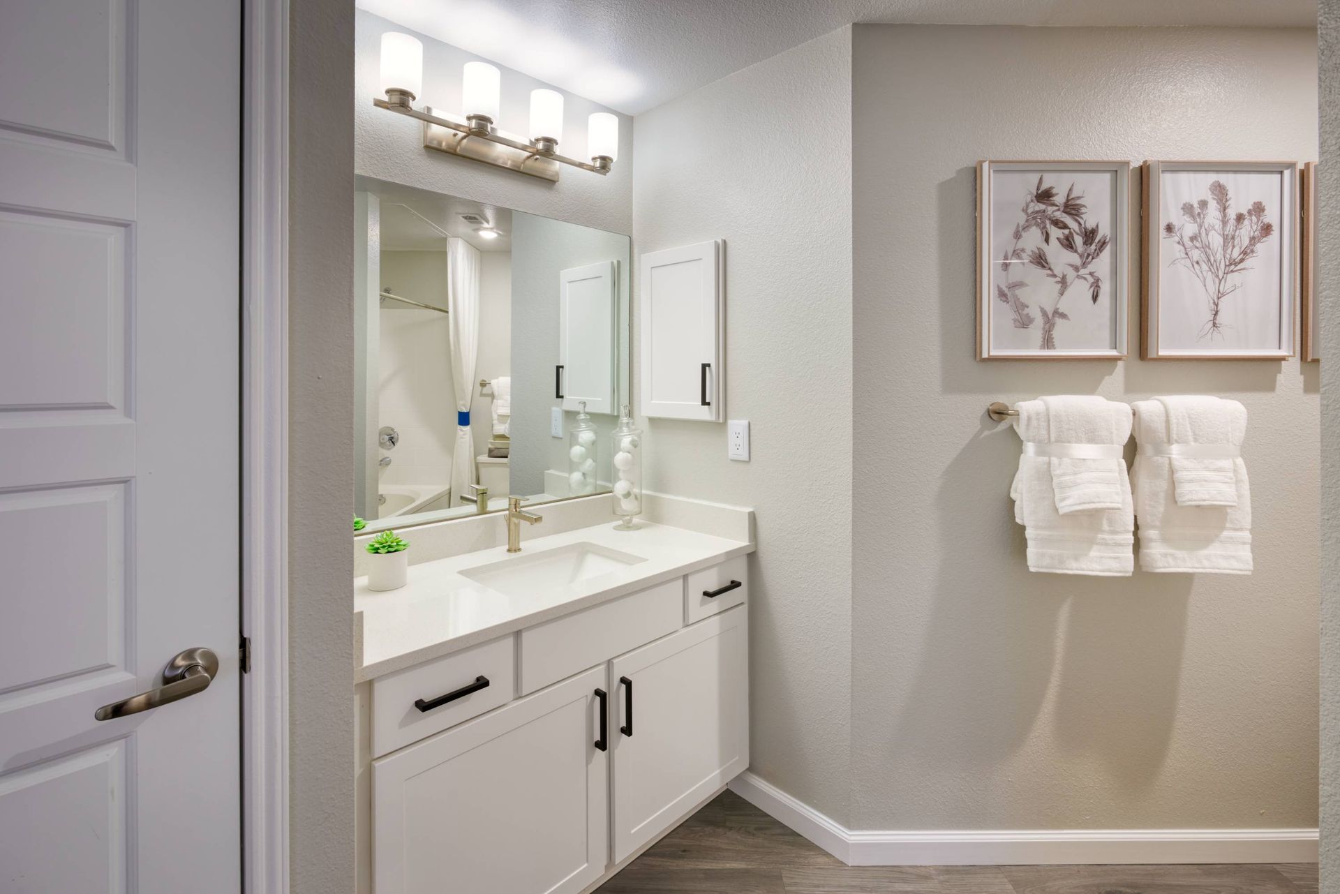Bathroom vanity with white cabinetry, mirror, and towel rack.