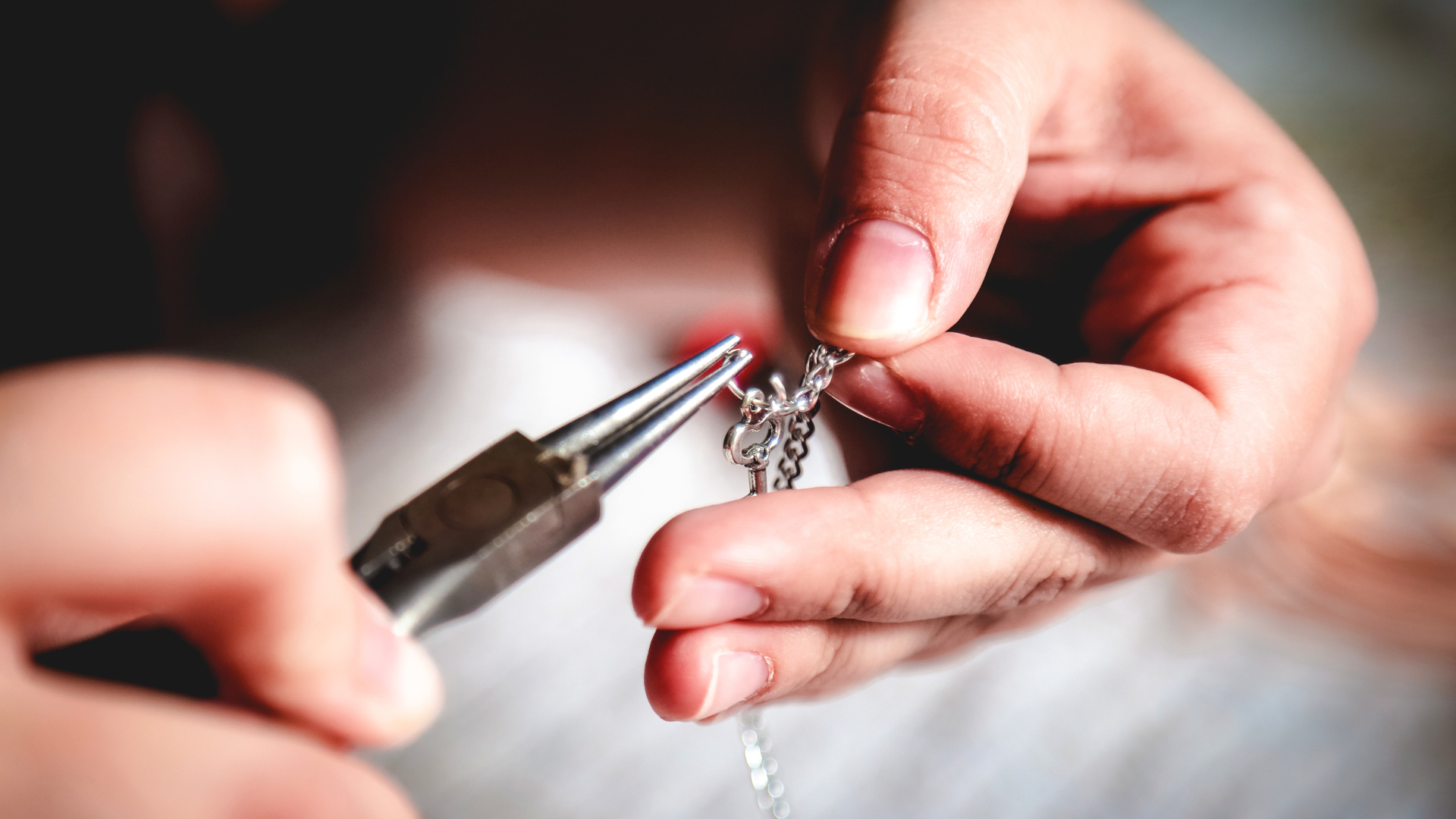 A person is making a necklace with pliers.