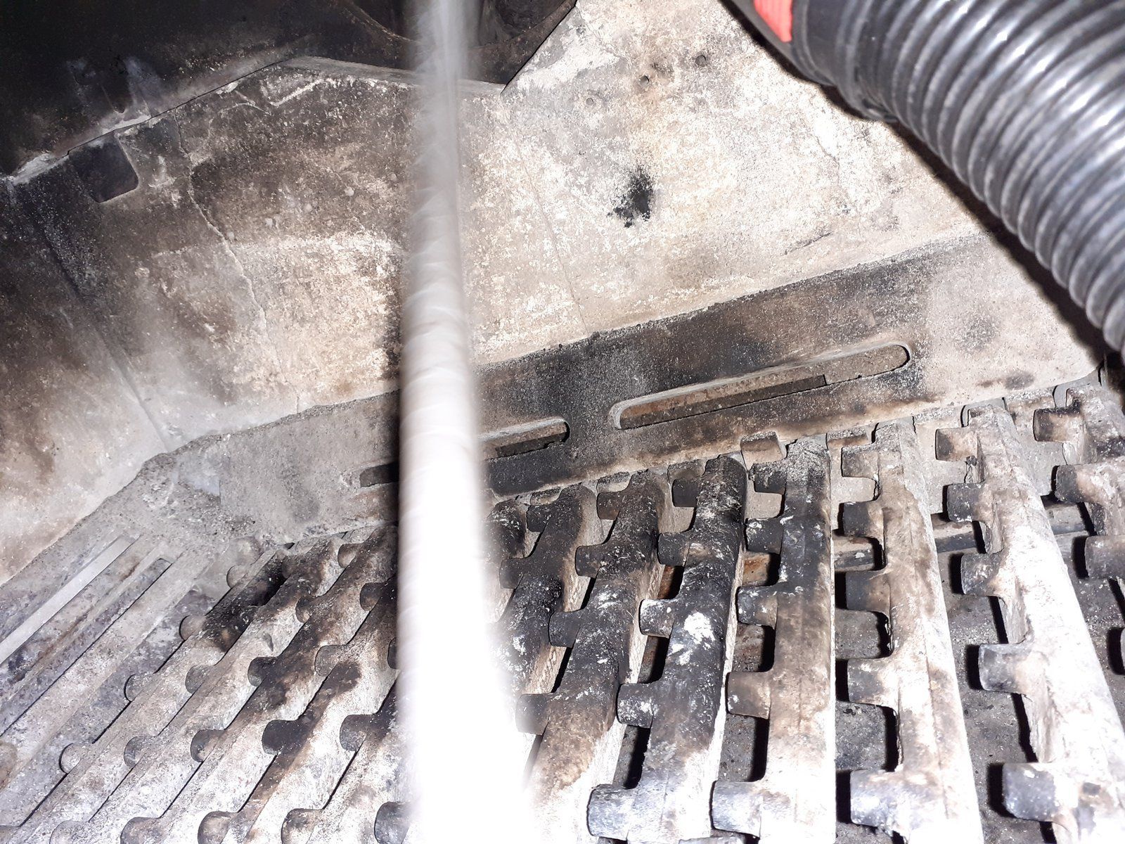 Gros plan sur une grille métallique sale avec un tuyau ou un câble dans un environnement industriel poussiéreux