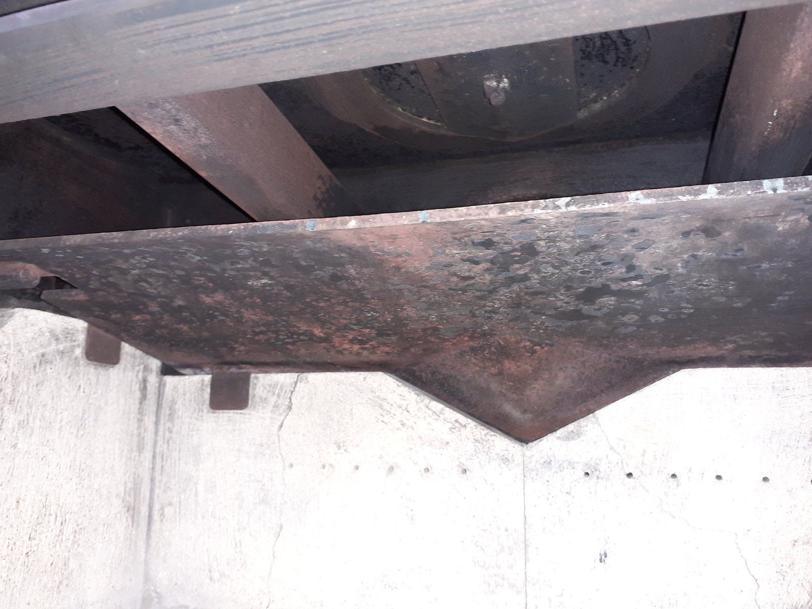 Poutre métallique rouillée avec un support triangulaire sous une surface en béton