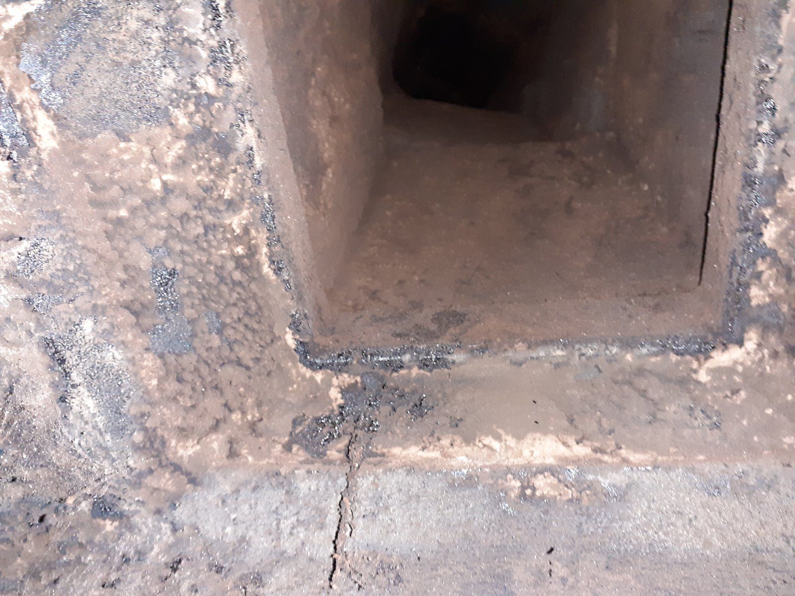 Gros plan sur une ouverture ou un évent métallique rouillé encastré dans une surface en béton.