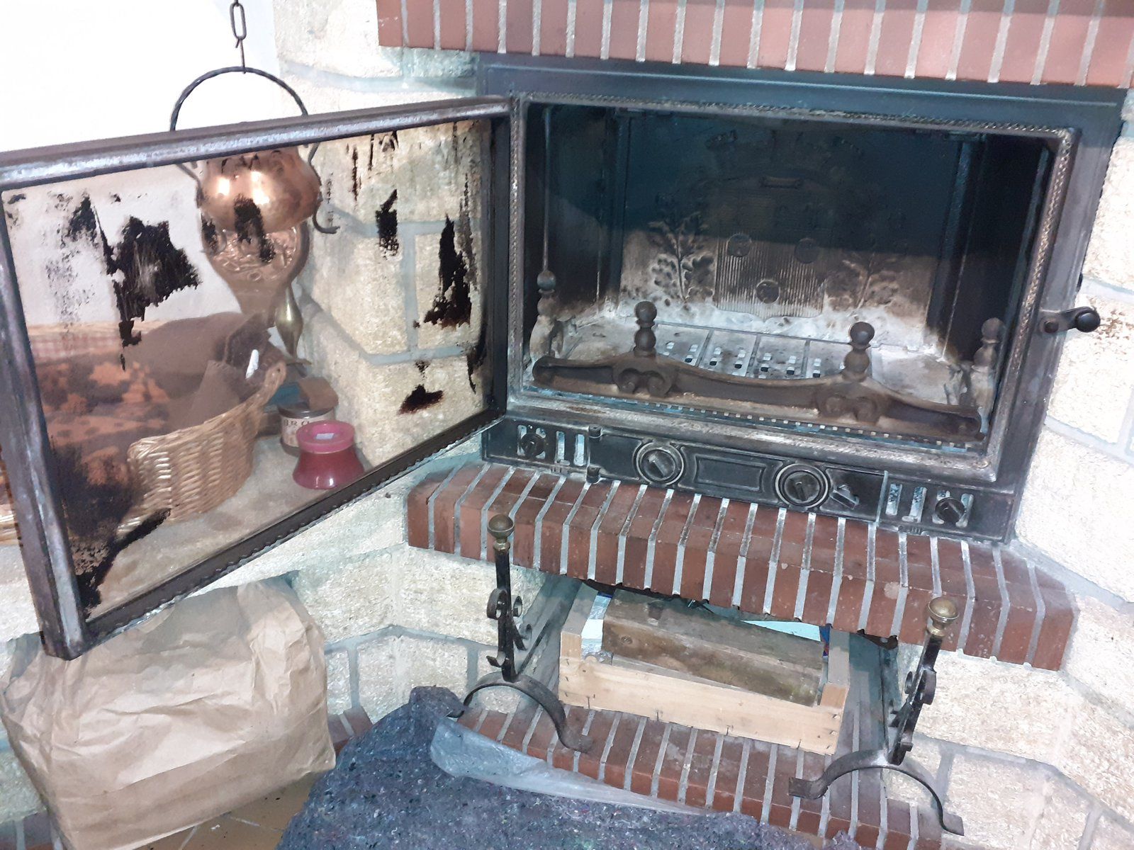 Cheminée extérieure en briques avec portes vitrées ouvertes et grille de barbecue en métal à l'intérieur
