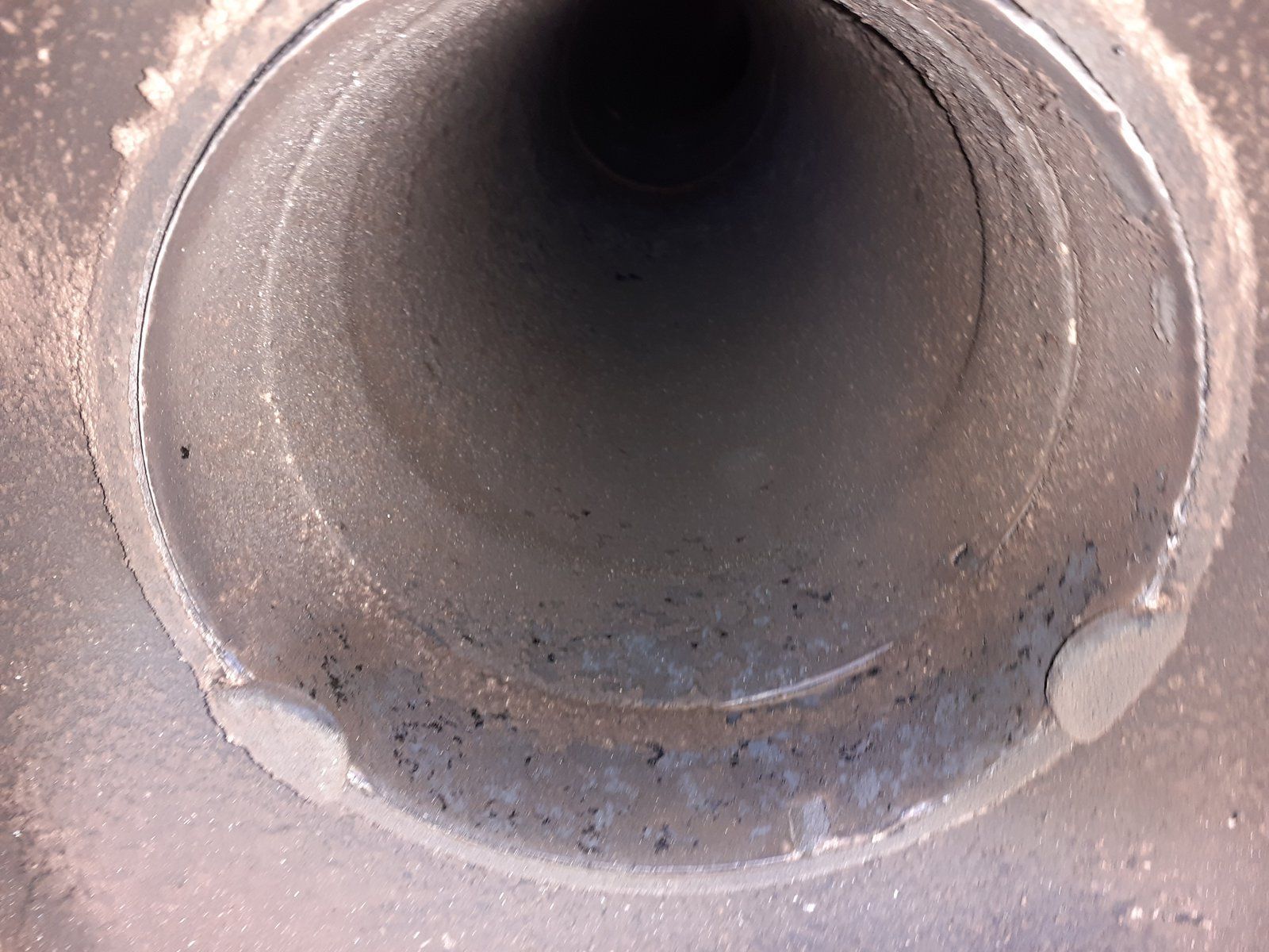 Gros plan sur l'intérieur d'un tuyau circulaire en béton avec une ouverture sombre et des parois gris poussiéreuses