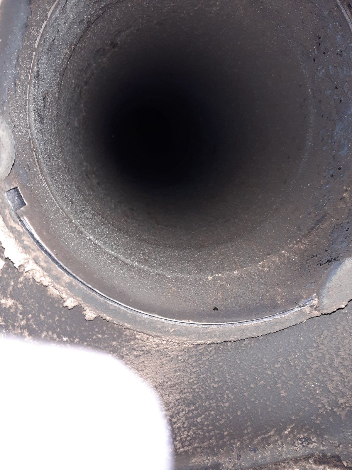 Gros plan sur l'ouverture d'un tuyau circulaire sombre avec des surfaces intérieures grises et poussiéreuses