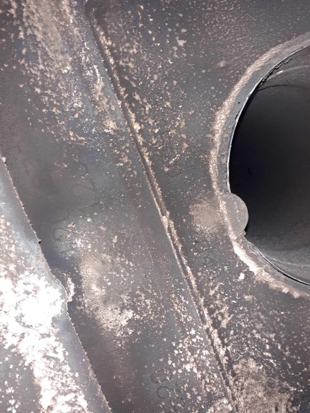 Gros plan sur une surface métallique gris poussiéreux présentant un trou circulaire sur le côté droit.